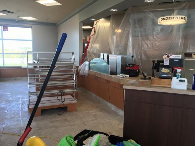 Restaurant counter area with plastic barriers, cleaning mop, and a