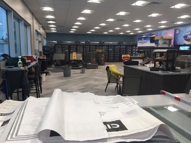 Modern office lounge with desks, chairs, bookshelves, and papers on a foreground table