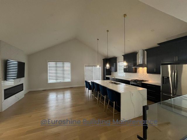 Open-concept kitchen and dining area with dark cabinets, island seating, and light wood floors