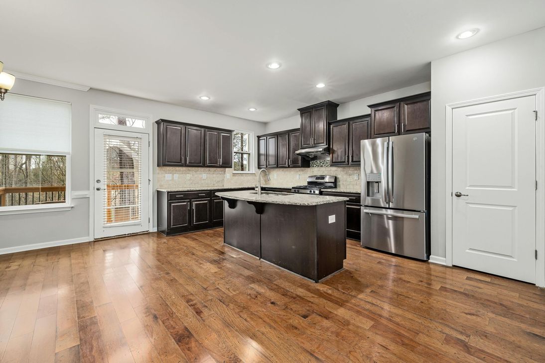 Kitchen with dark cabinets, stainless steel appliances, and wood floors.