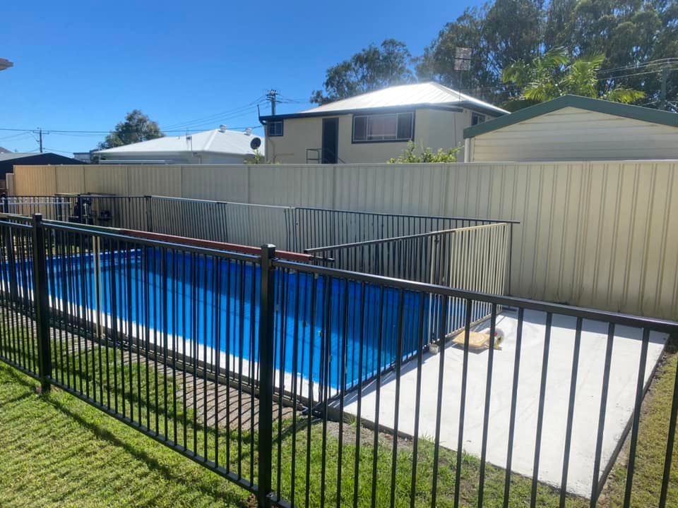 A Fence Surrounds A Large Swimming Pool In A Backyard — Arecta Fence In Lakewood, NSW