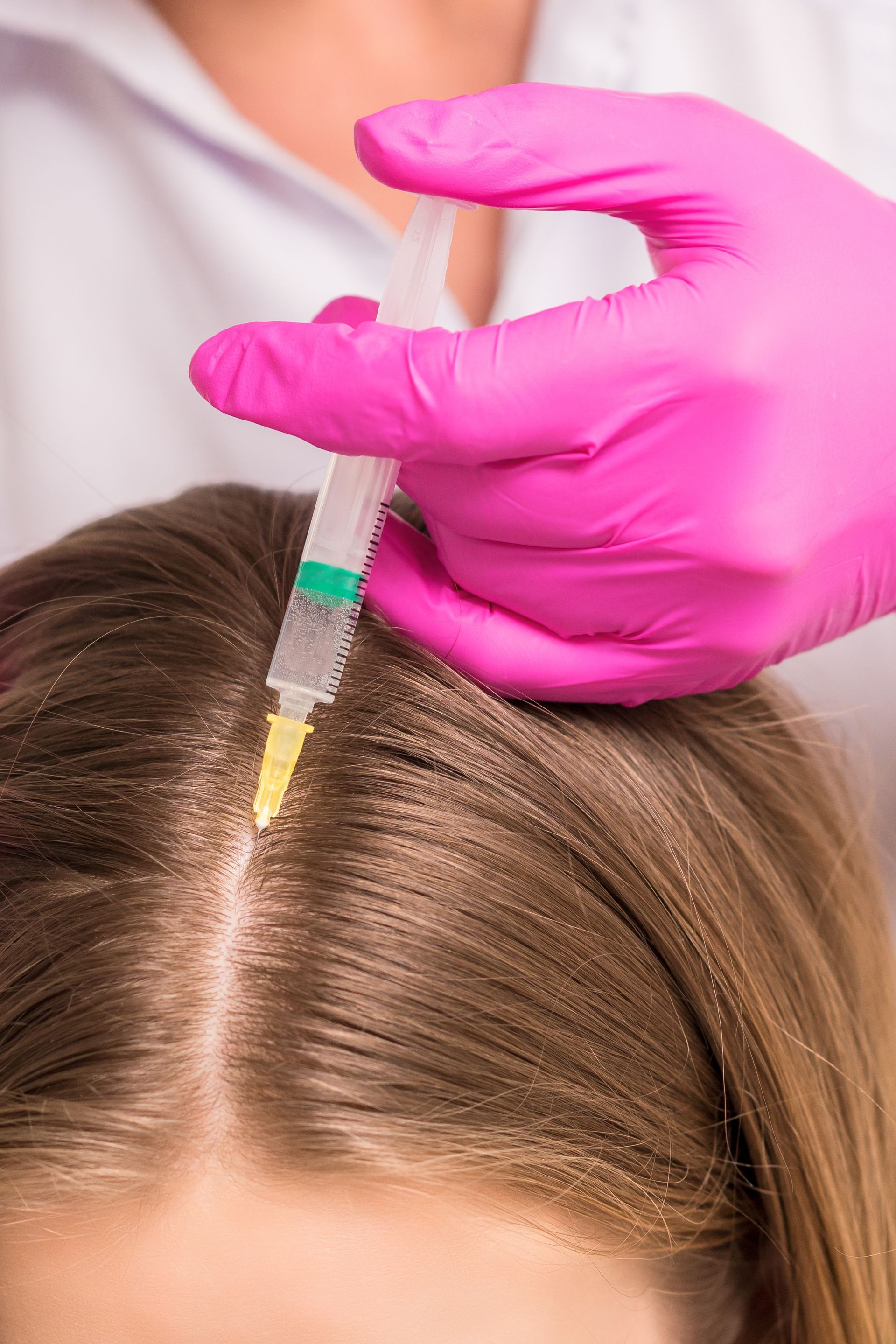 A woman is getting an injection in her hair.