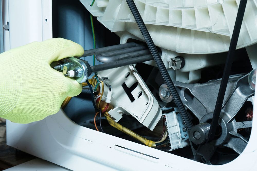 A Person is Working on a Washing Machine With a Wrench — Patrick Lunney Home Appliance Service & Repairs in Maudsland, QLD