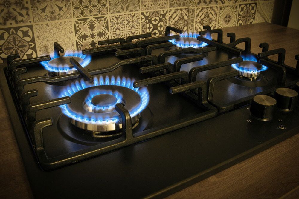A Gas Stove With Four Burners is Lit Up in a Kitchen — Patrick Lunney Home Appliance Service & Repairs in Maudsland, QLD