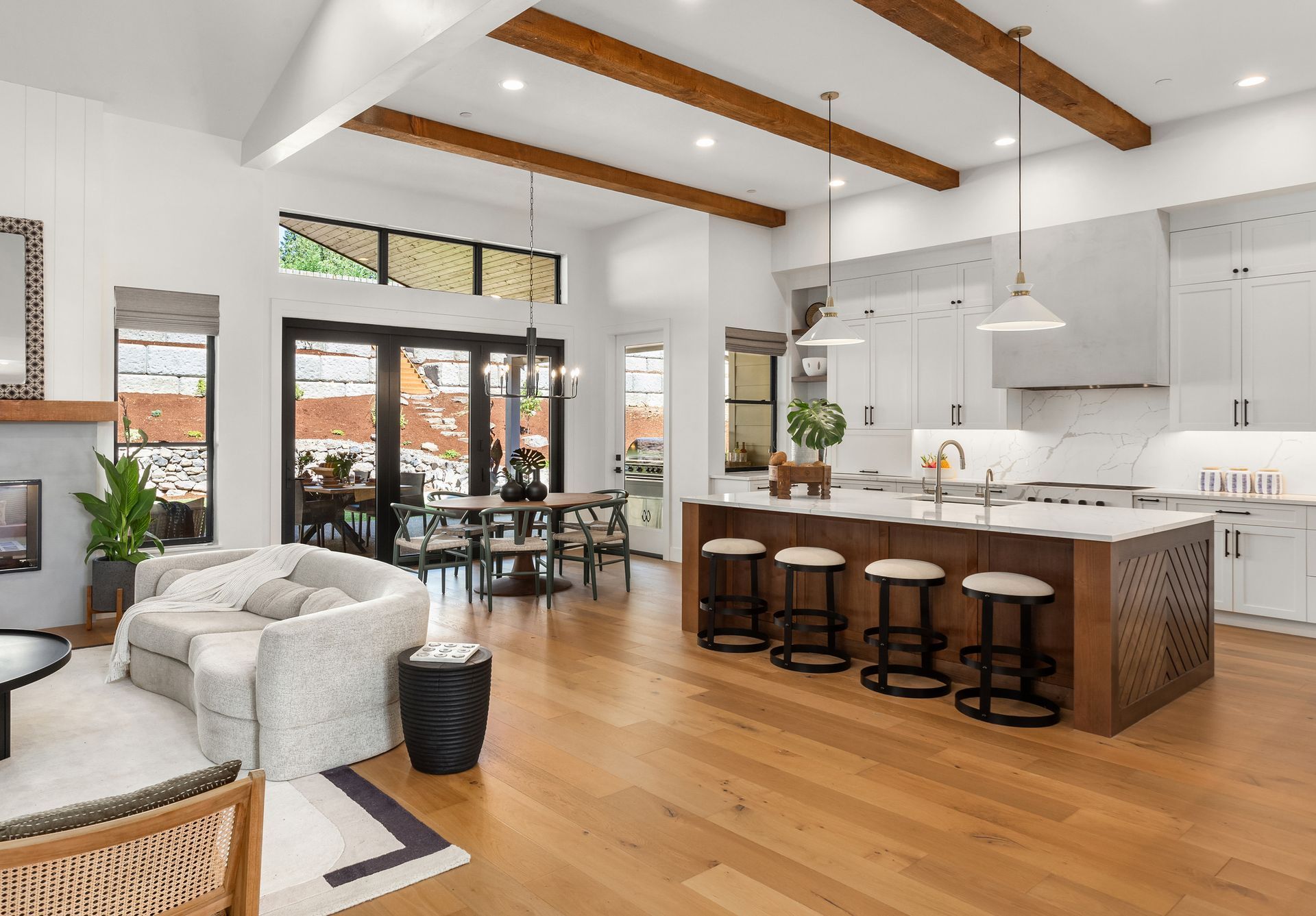 A living room and kitchen in a house with hardwood floors and white cabinets.
