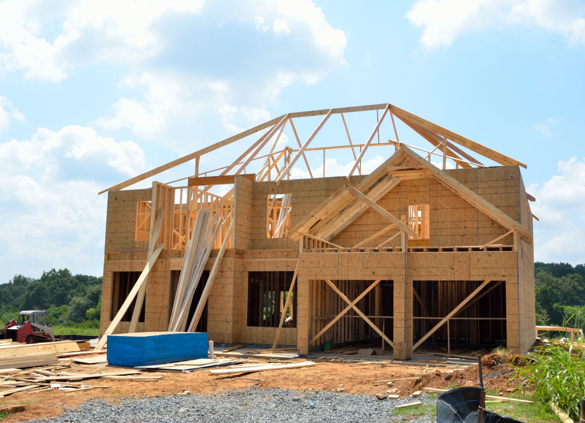 A large wooden house is being built on a dirt field.