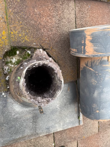 Avented pipe on a rooftop with a build-up of debris inside.