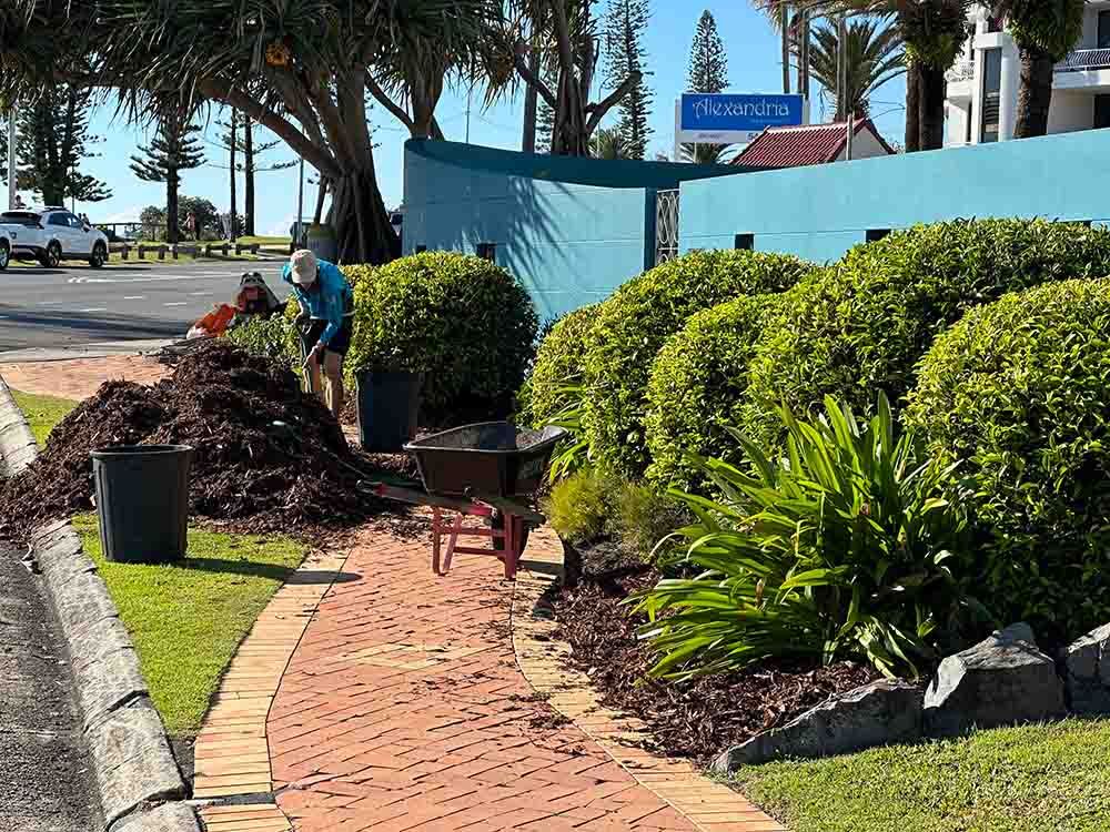 A Man Shoveling Soil In A Garden— Hallsmark Property Services
