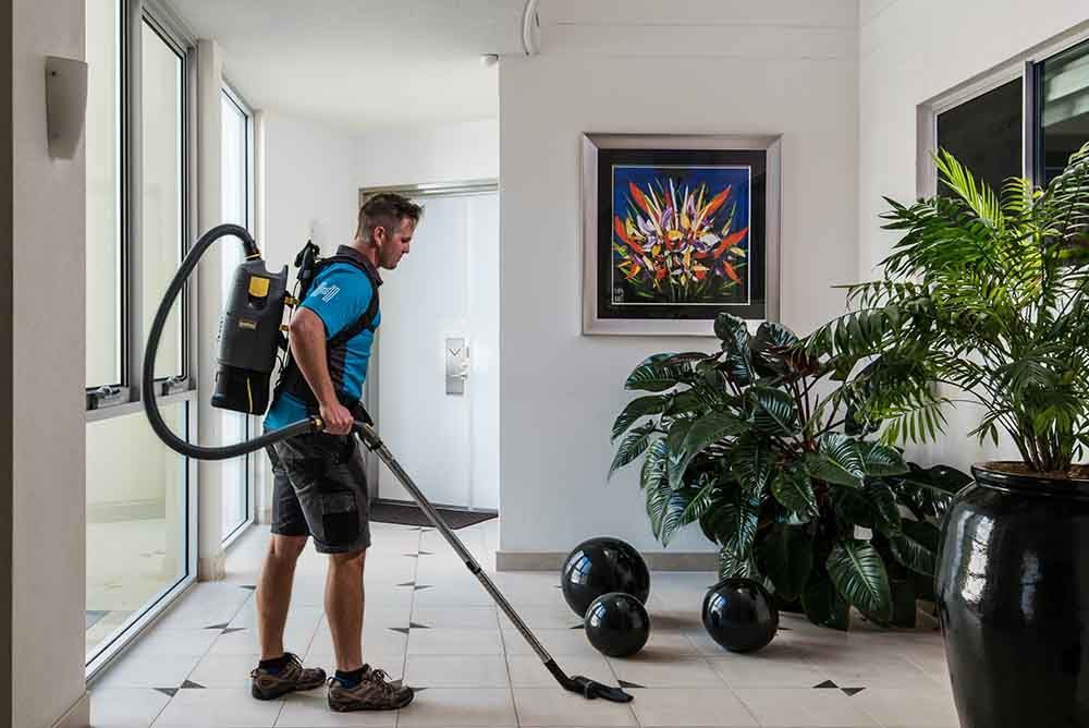 Man Cleaning Floor With Vacuum Cleaner — Hallsmark Property Services