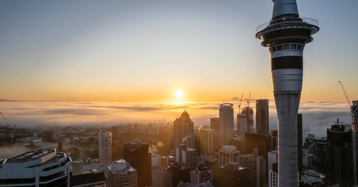 The sun is setting over a city with a tower in the foreground.