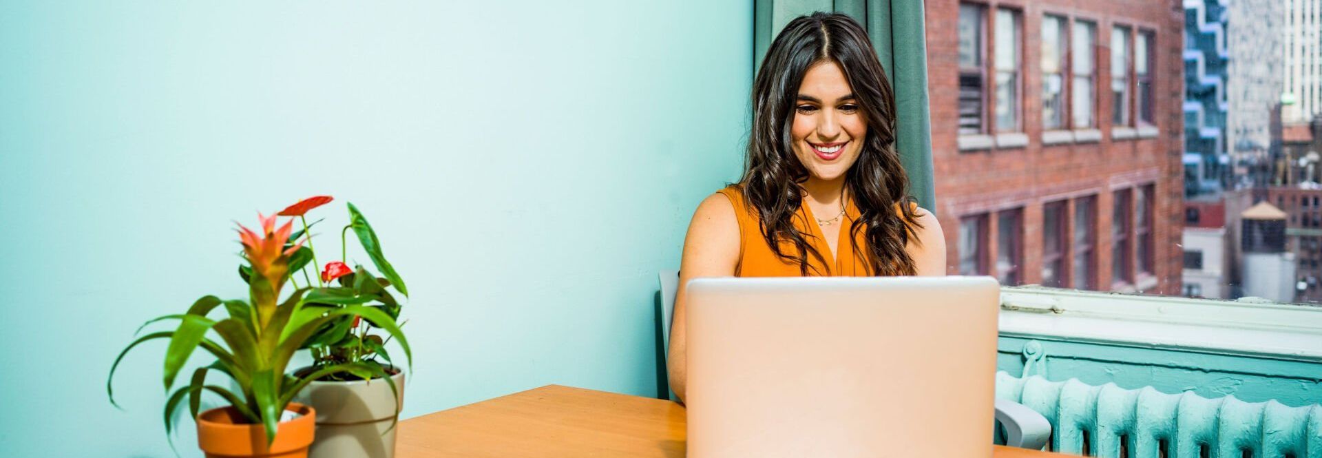 A woman is sitting at a desk using a laptop computer.