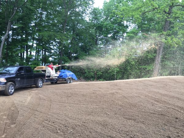 A truck is spraying fertilizer on a dirt field.