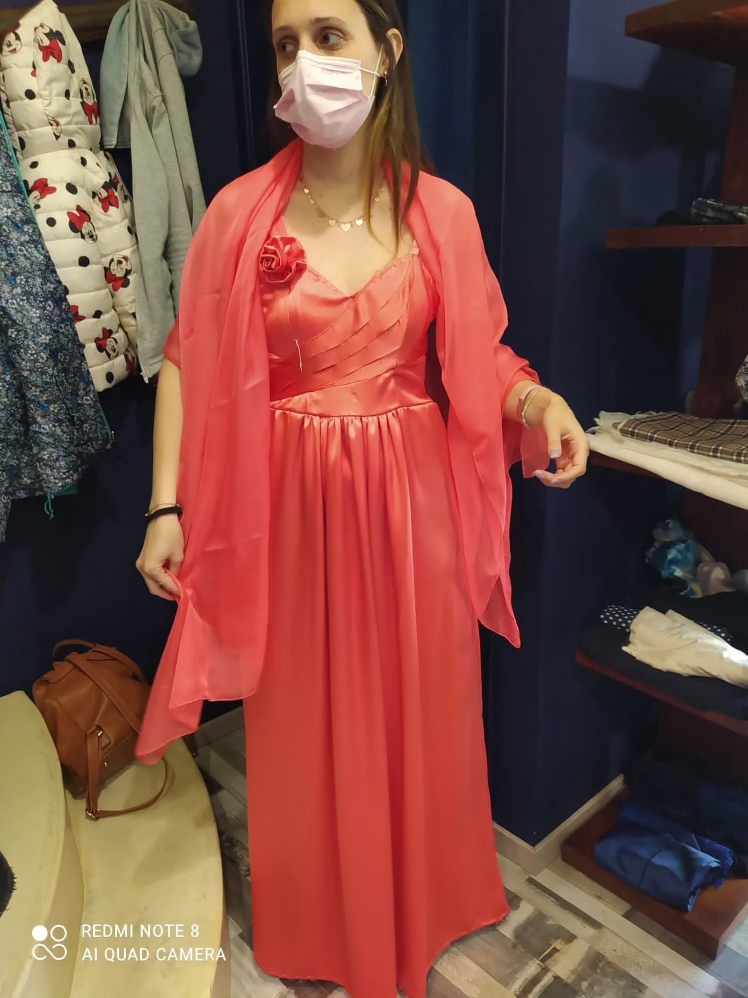 Una donna che indossa una maschera e un vestito rosso è in piedi in un armadio.