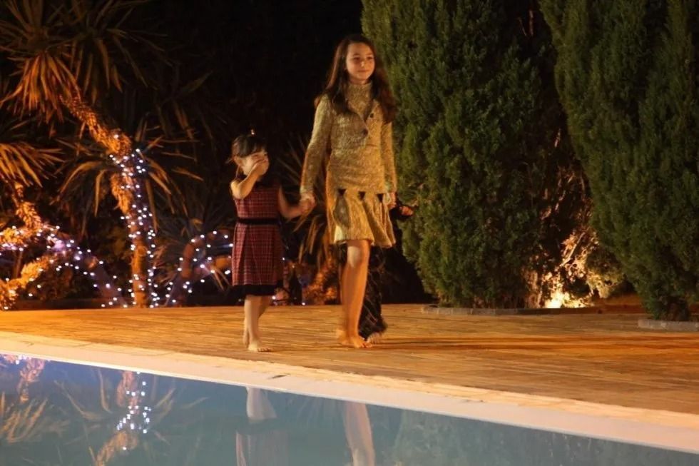 Due ragazzine camminano a piedi nudi a bordo piscina di notte.