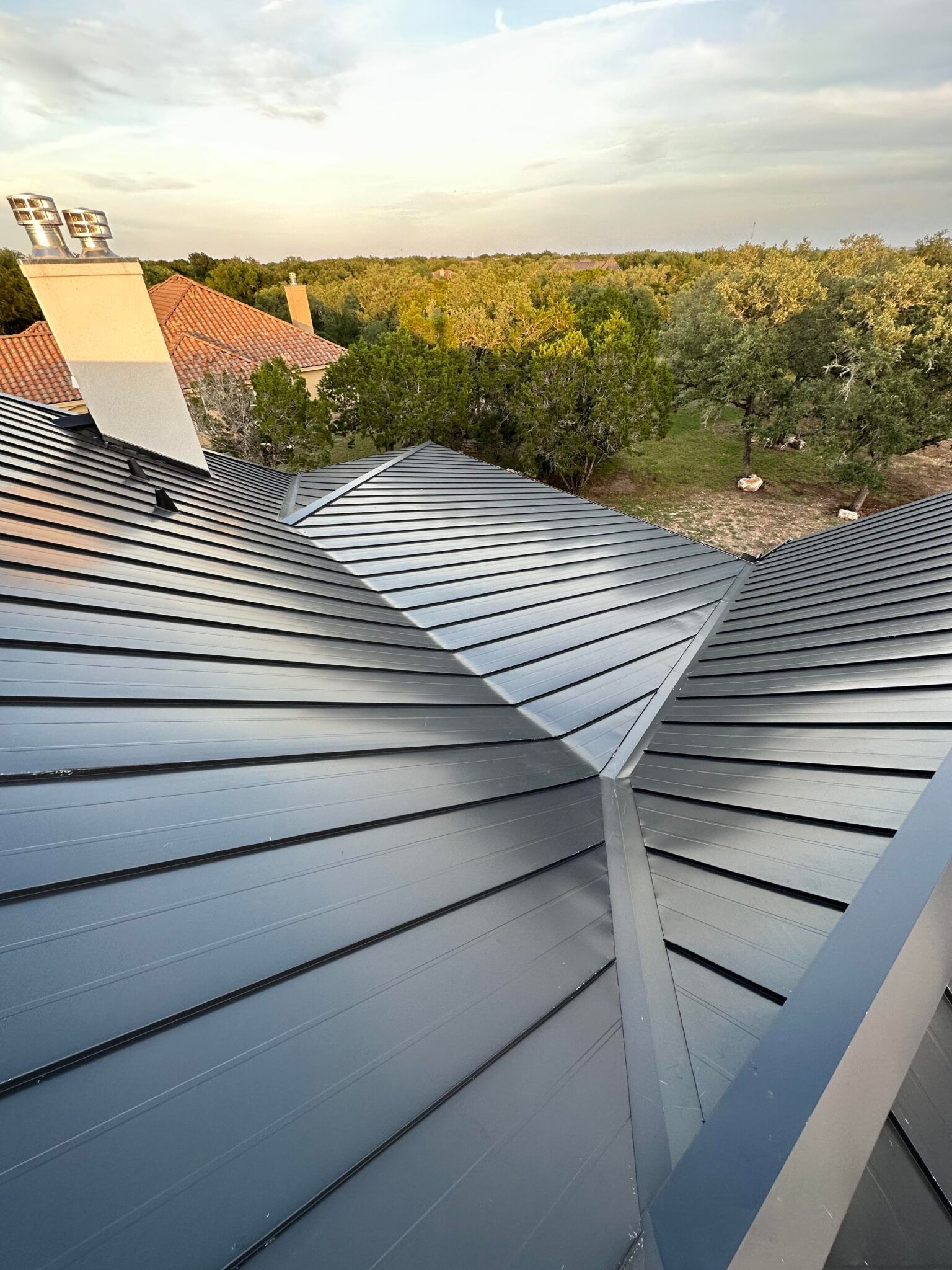 A close up of a metal roof with trees in the background.