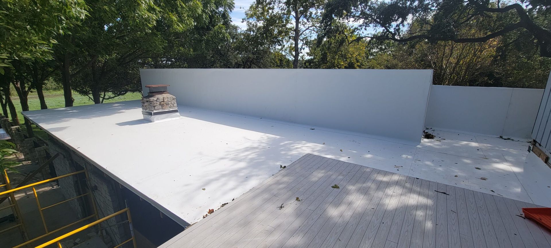 A white roof with trees in the background is being built.