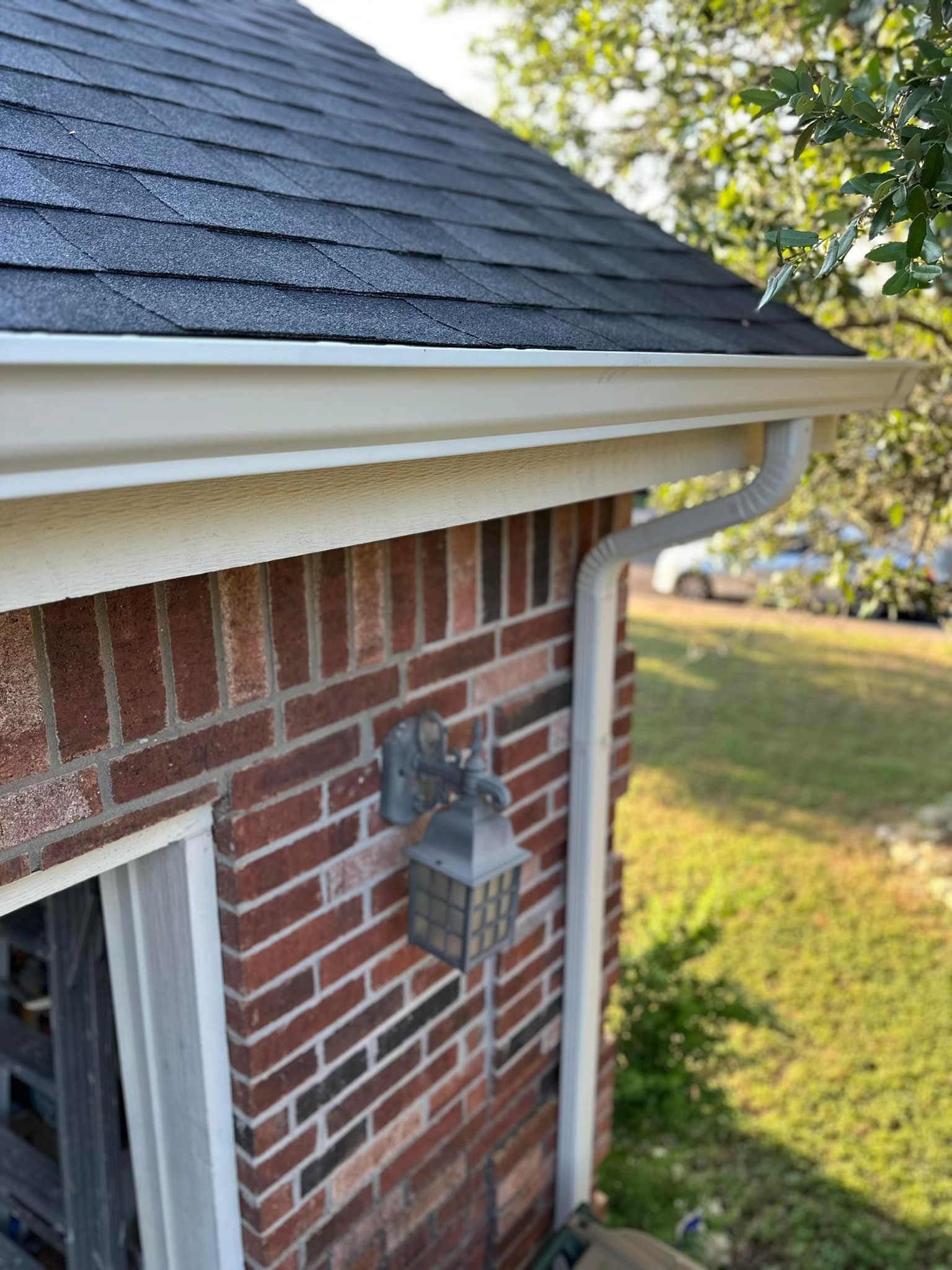 A brick house with a white gutter and a black roof.