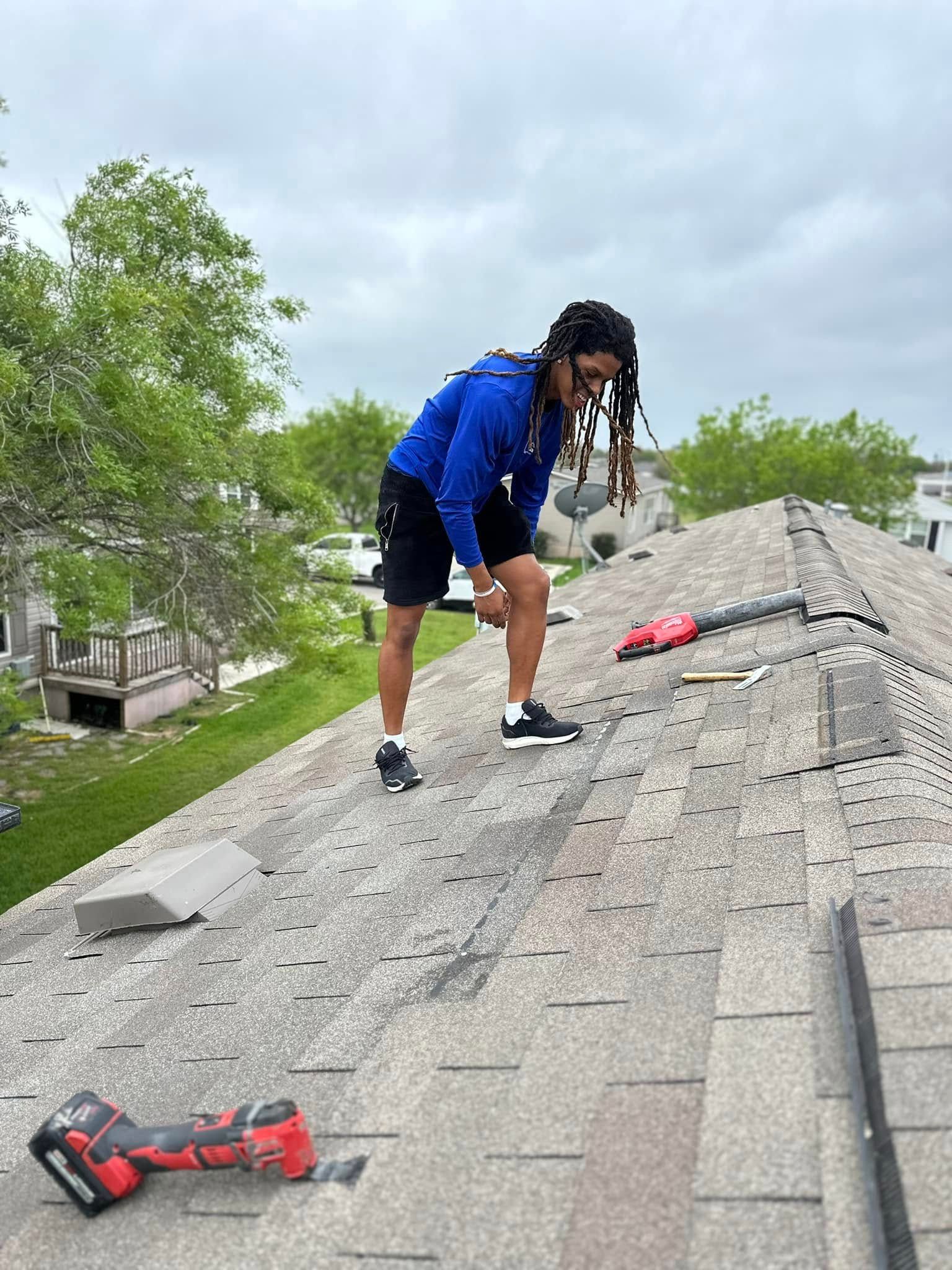 A man is standing on top of a roof working on it.