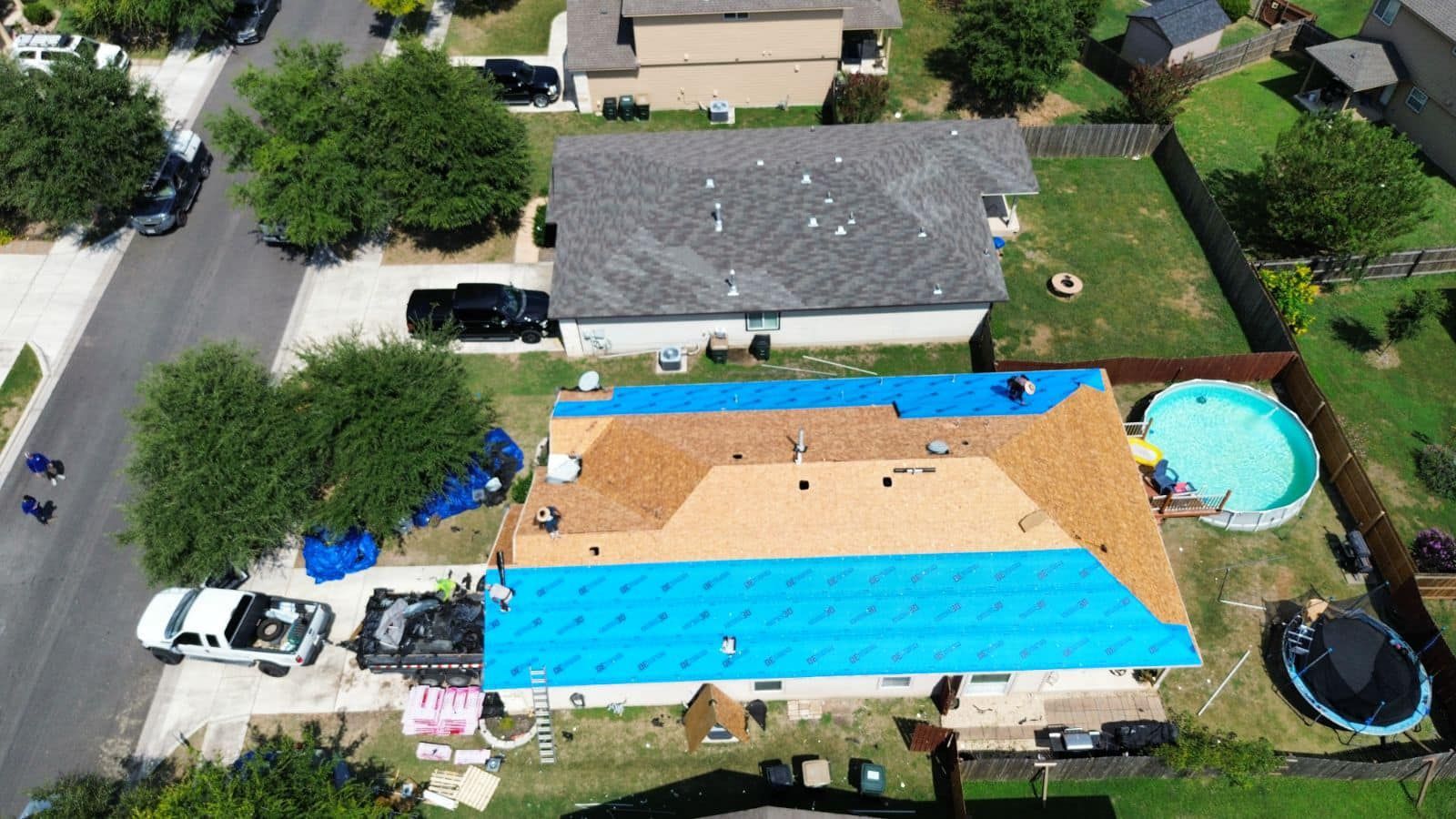 An aerial view of a house with a blue tarp on the roof.