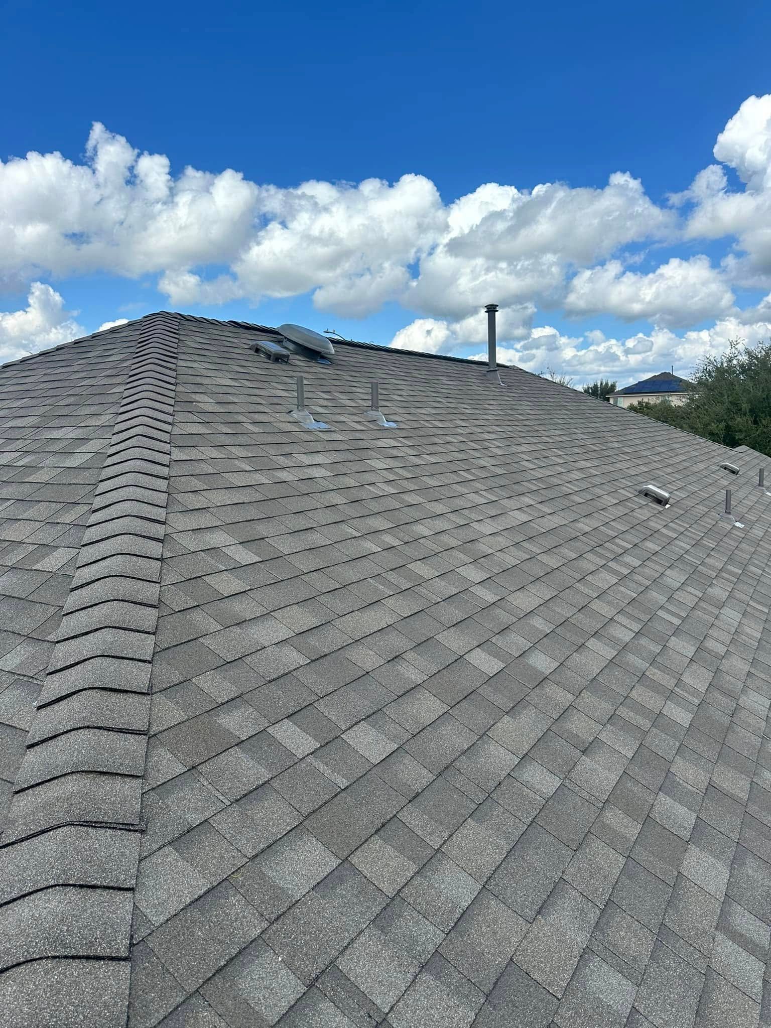 A close up of a roof with a blue sky and clouds in the background.