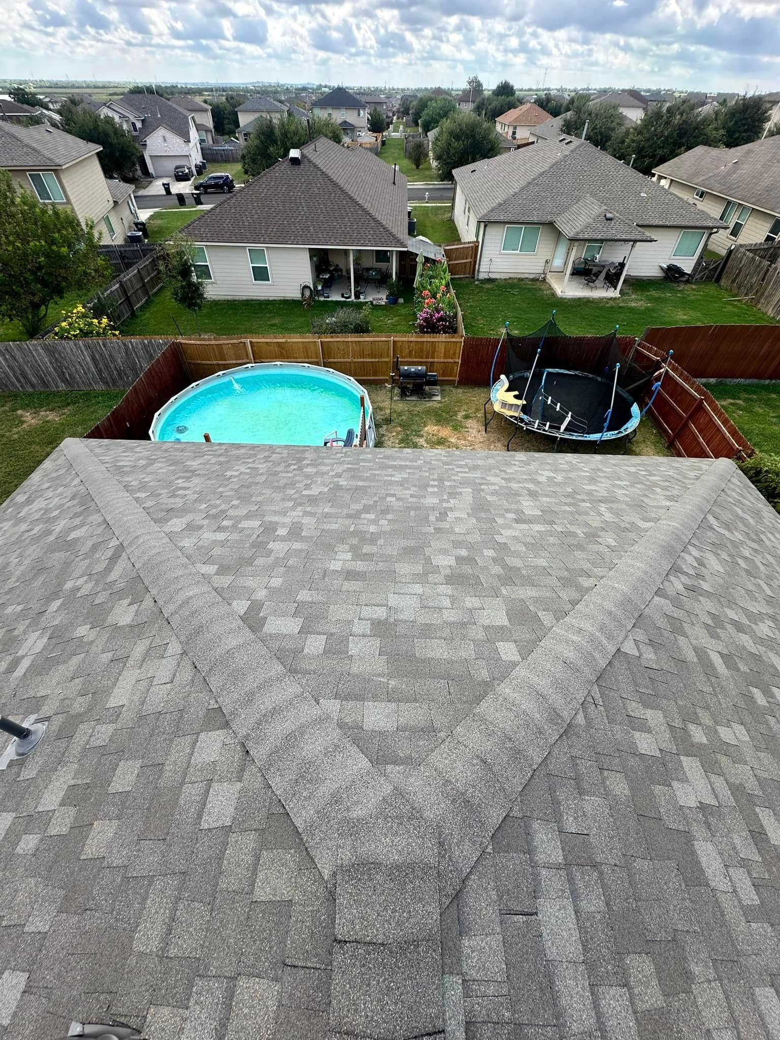 An aerial view of a backyard with a pool and trampoline.