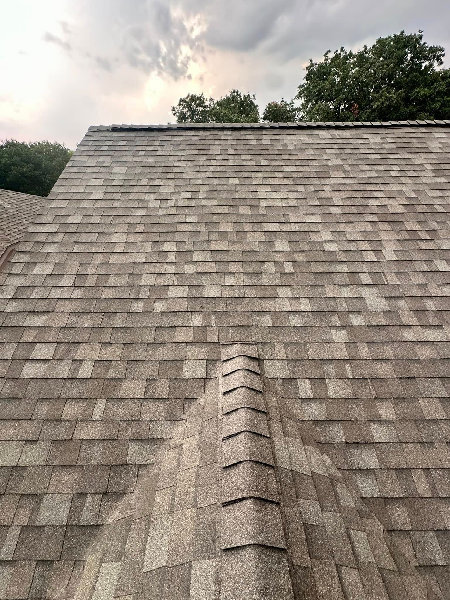 Looking up at a roof with a cloudy sky in the background.