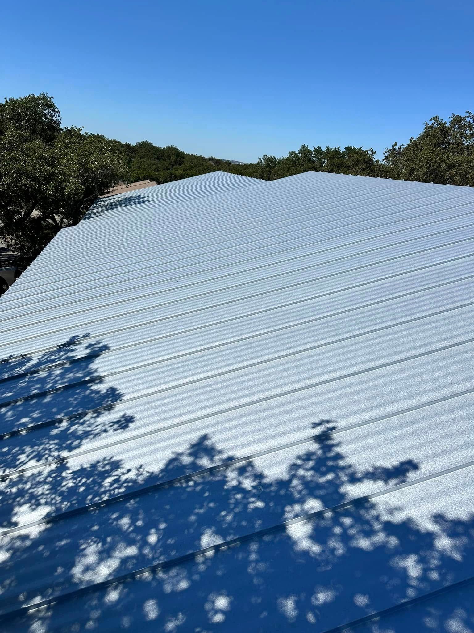 A white roof with trees in the background and a blue sky