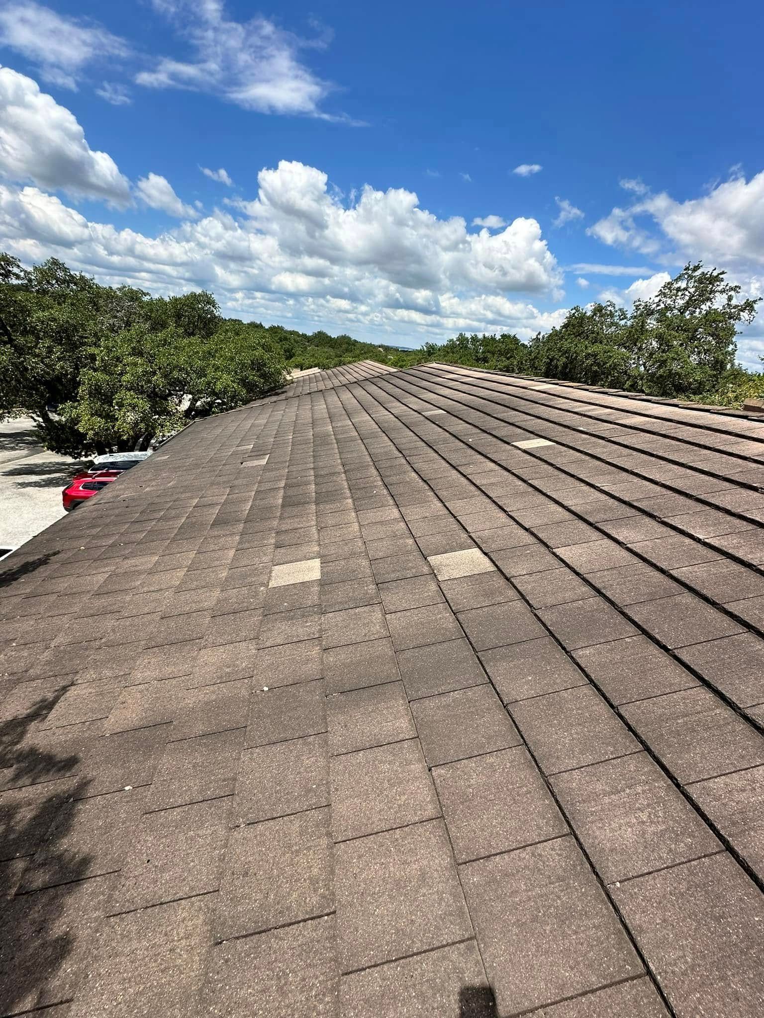 A close up of a roof with a blue sky and clouds in the background.