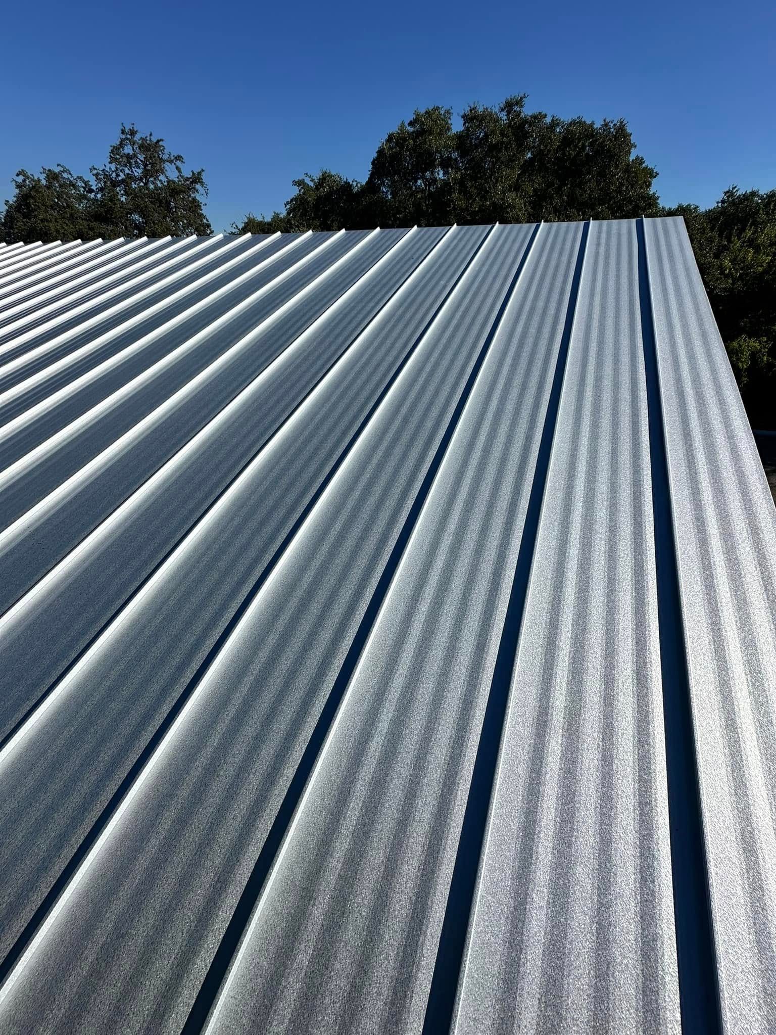 A close up of a metal roof with trees in the background.