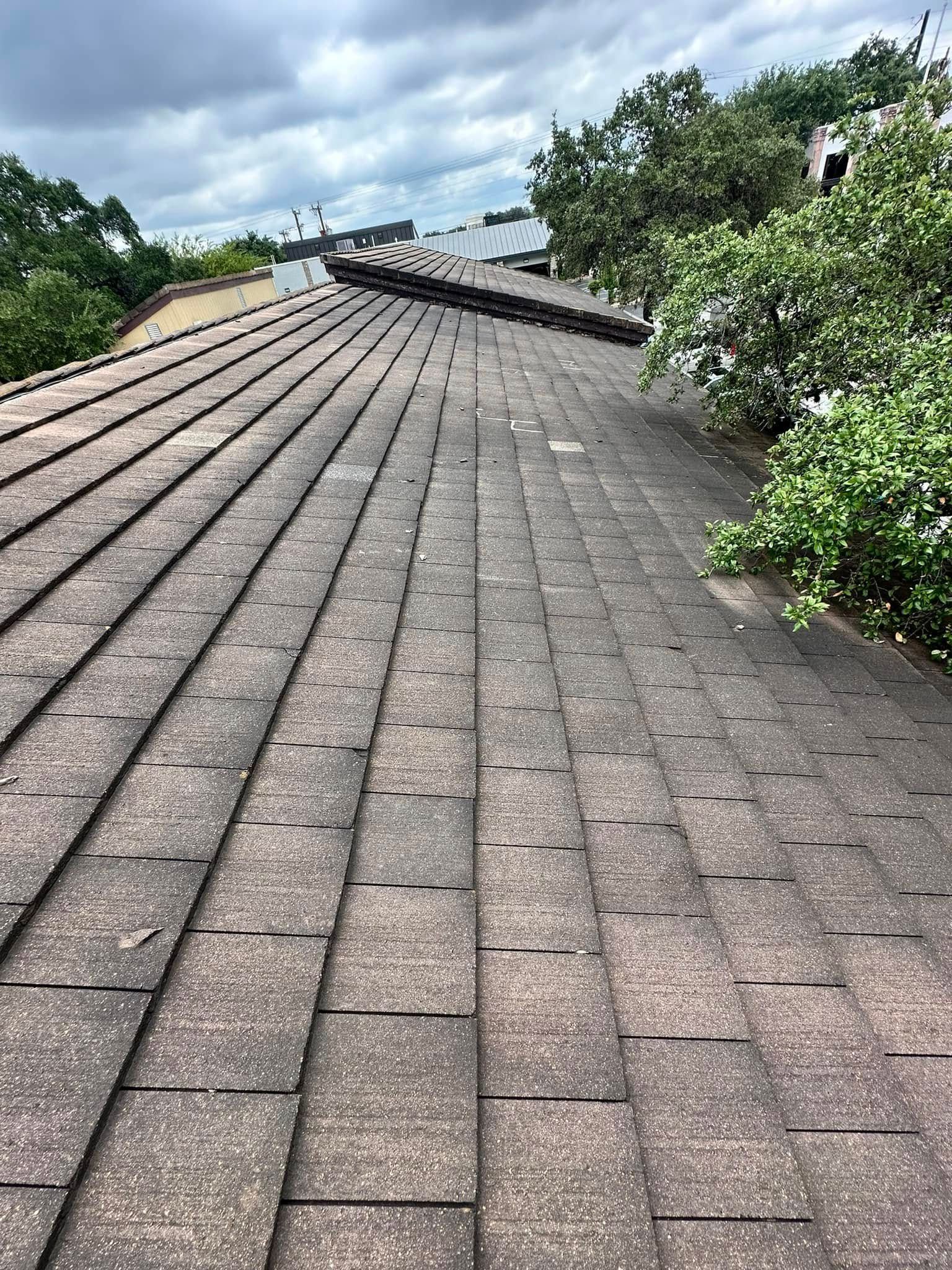 A roof with a lot of shingles on it and trees in the background.