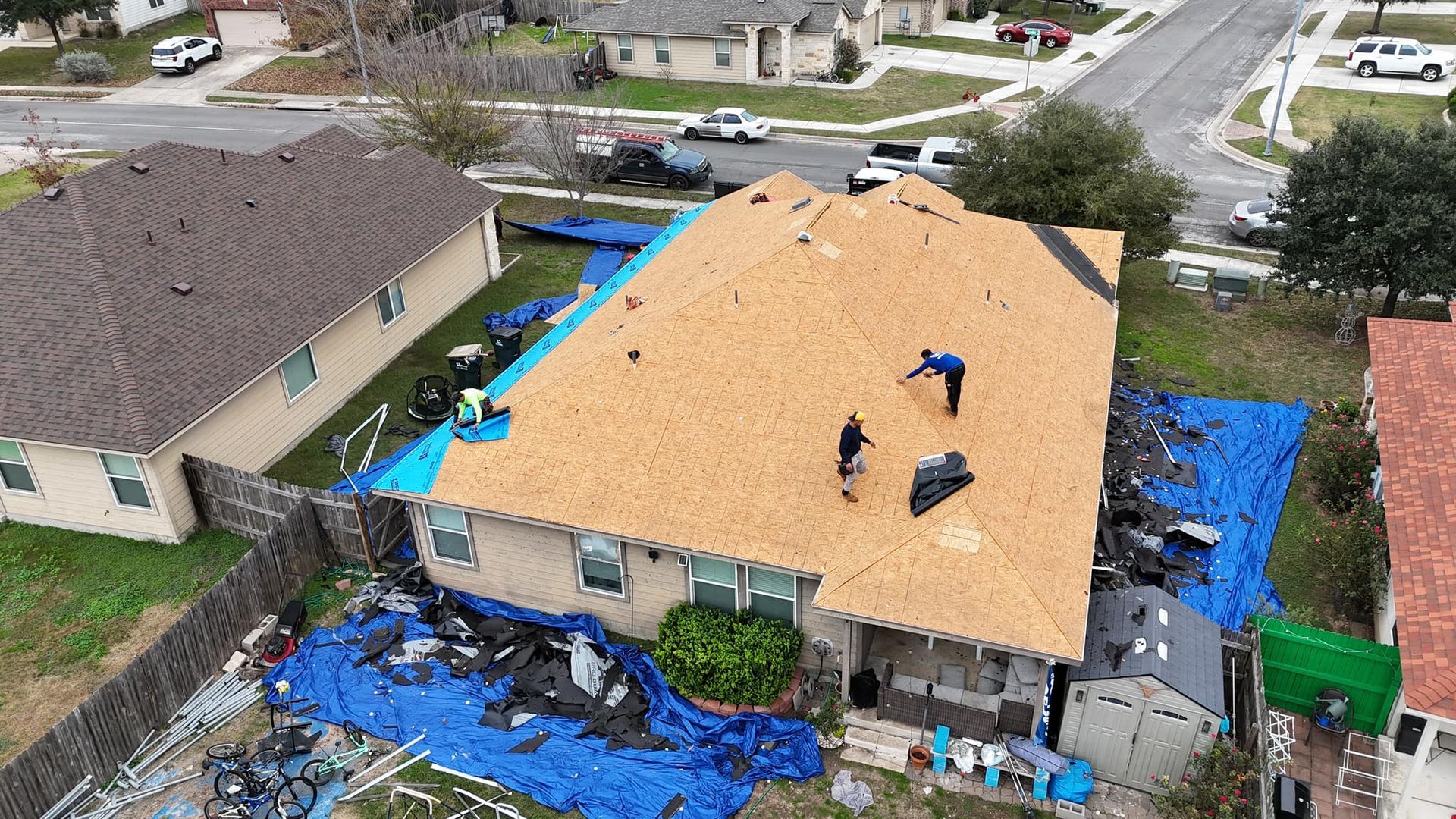 An aerial view of a house being roofed in a residential area.