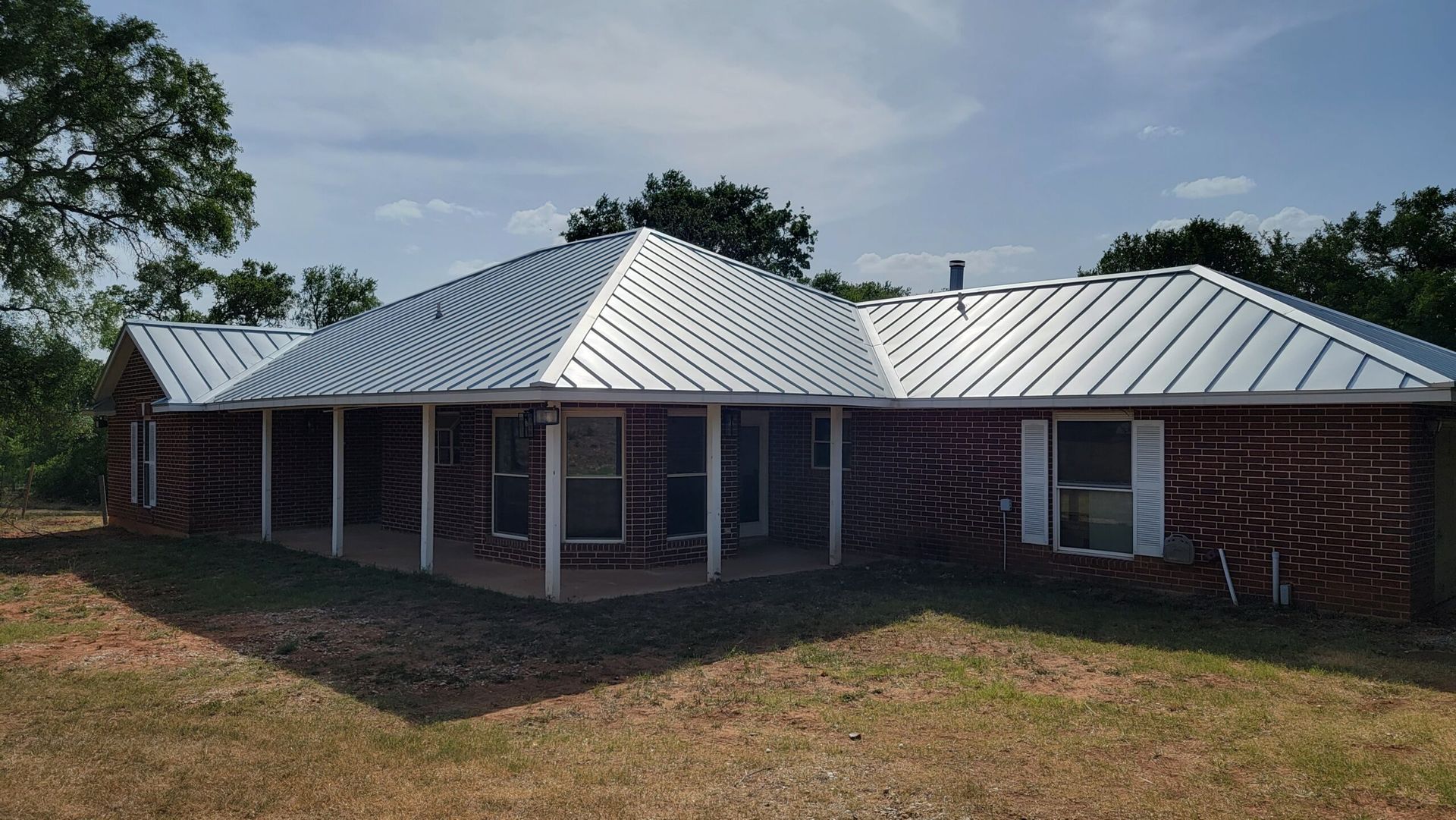 A brick house with a metal roof and a porch.