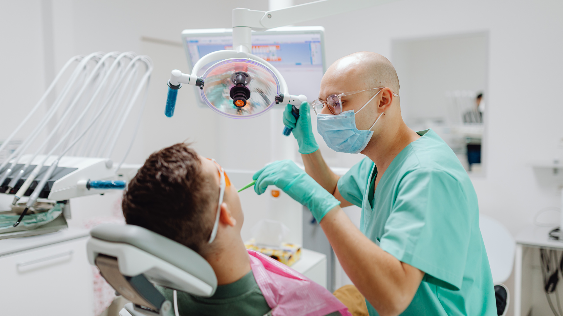 Dentist examining a patient's mouth with tools in a dental office.