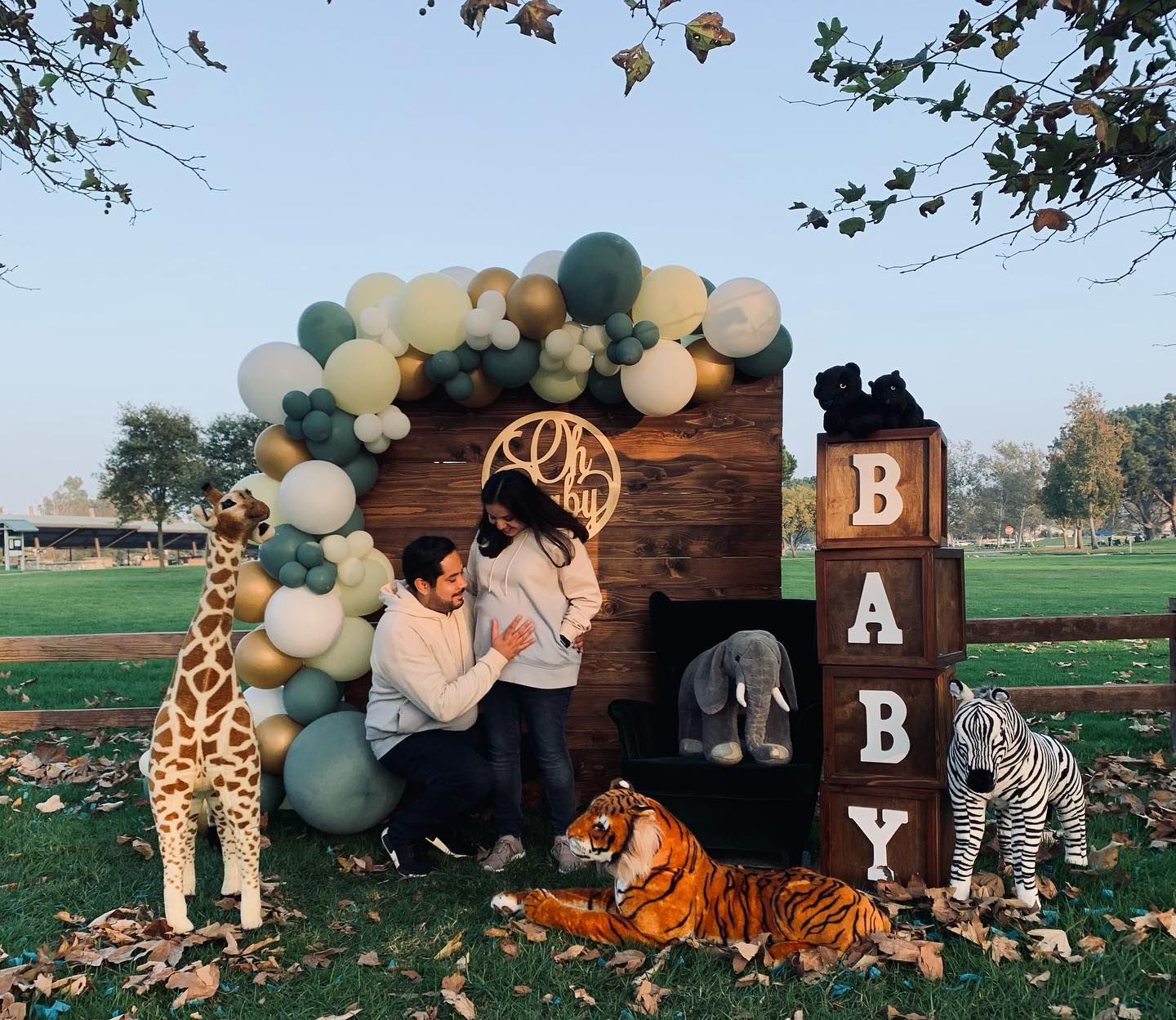 a man and woman are standing in front of a baby shower backdrop with stuffed animals and balloons