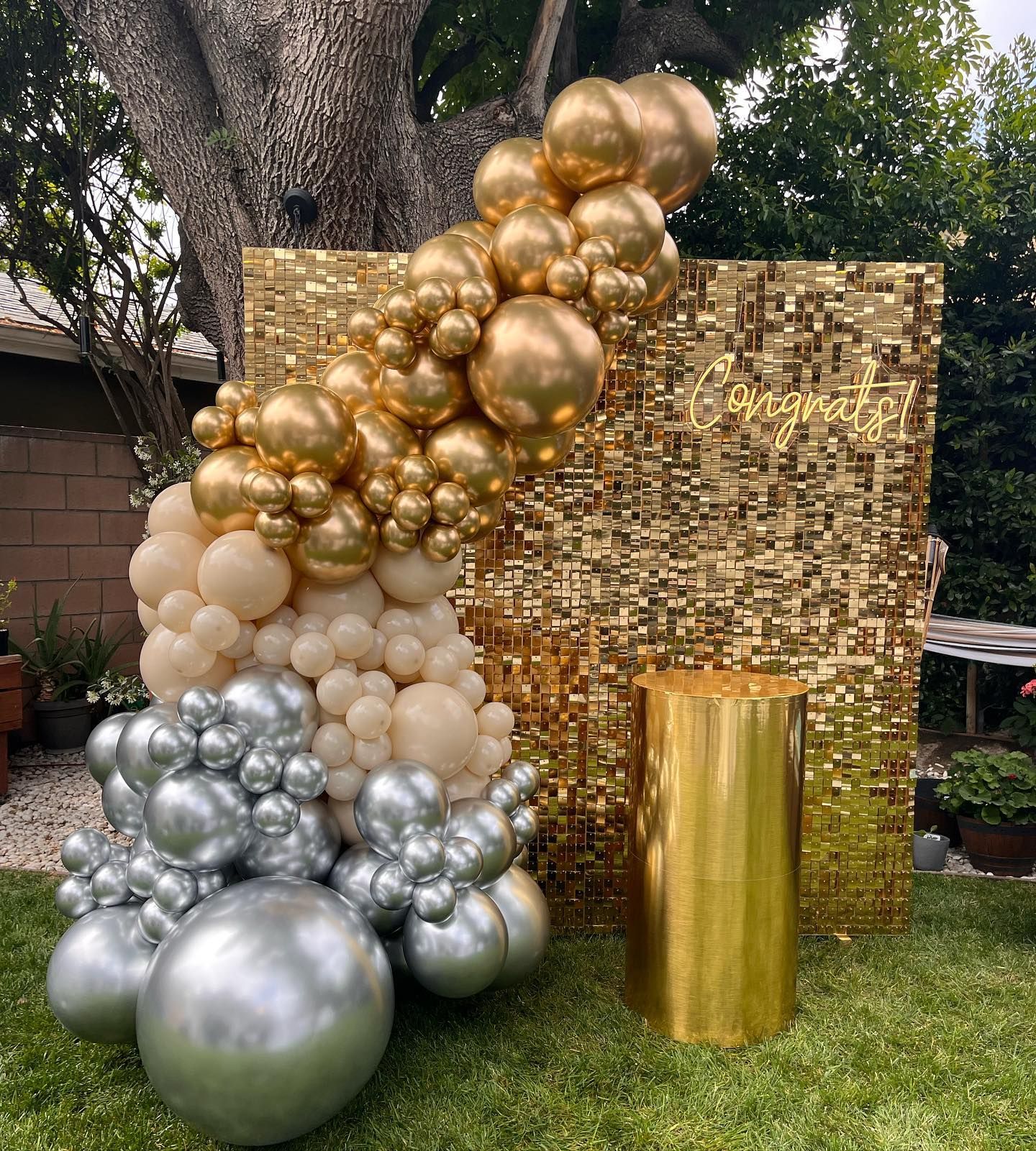 a bunch of gold and silver balloons are sitting in front of a gold wall