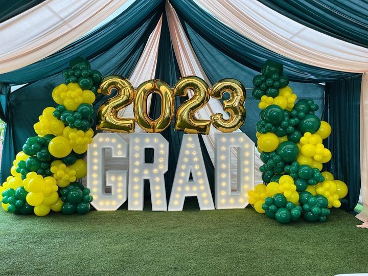 a sign that says 2023 grad is surrounded by green and yellow balloons