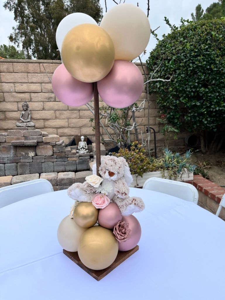 a teddy bear is sitting on top of a table with balloons