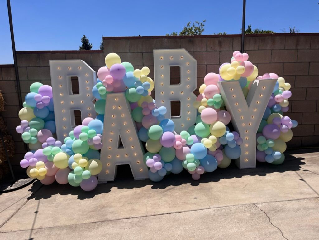 the word baby is surrounded by balloons and lights