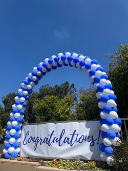 a blue and white balloon arch with a congratulations sign underneath it