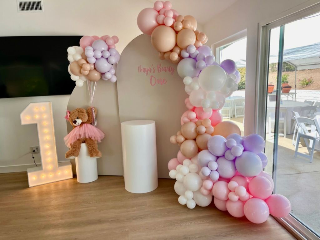 a room filled with balloons and a teddy bear