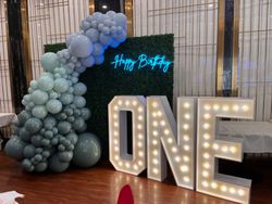 the word one is lit up in front of a wall of balloons