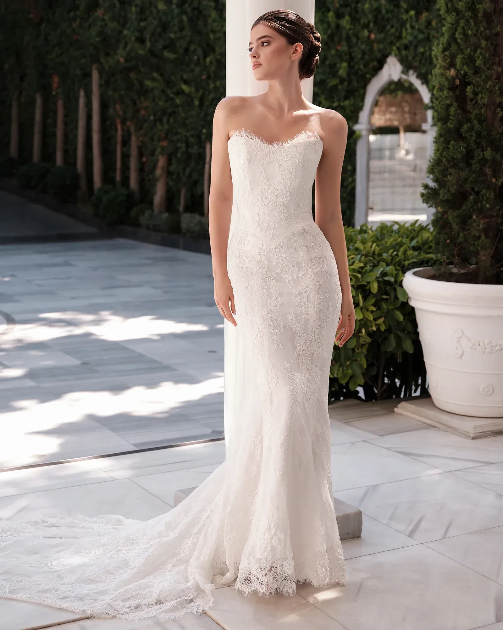 A woman in a white dress with a high slit is standing in front of a building.