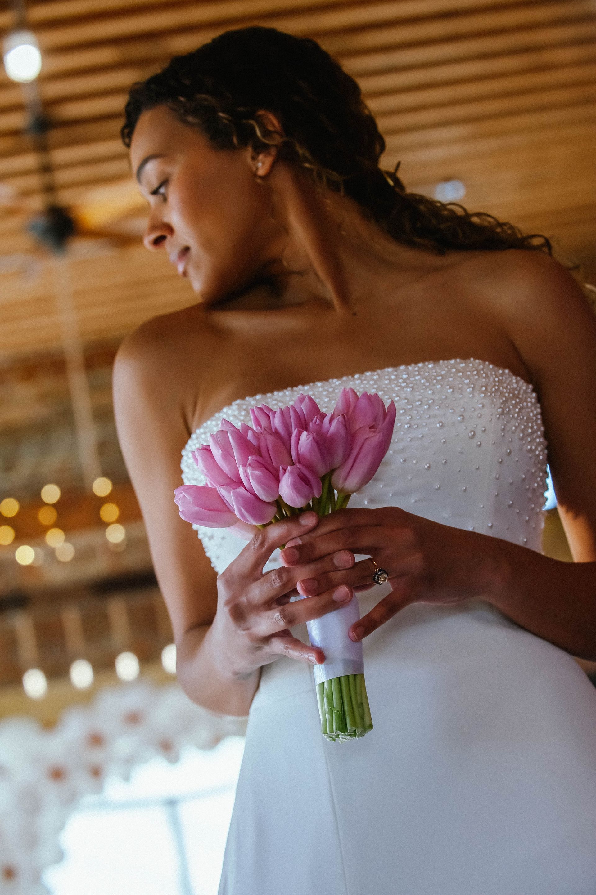 A woman in a wedding dress is holding a bouquet of pink flowers.