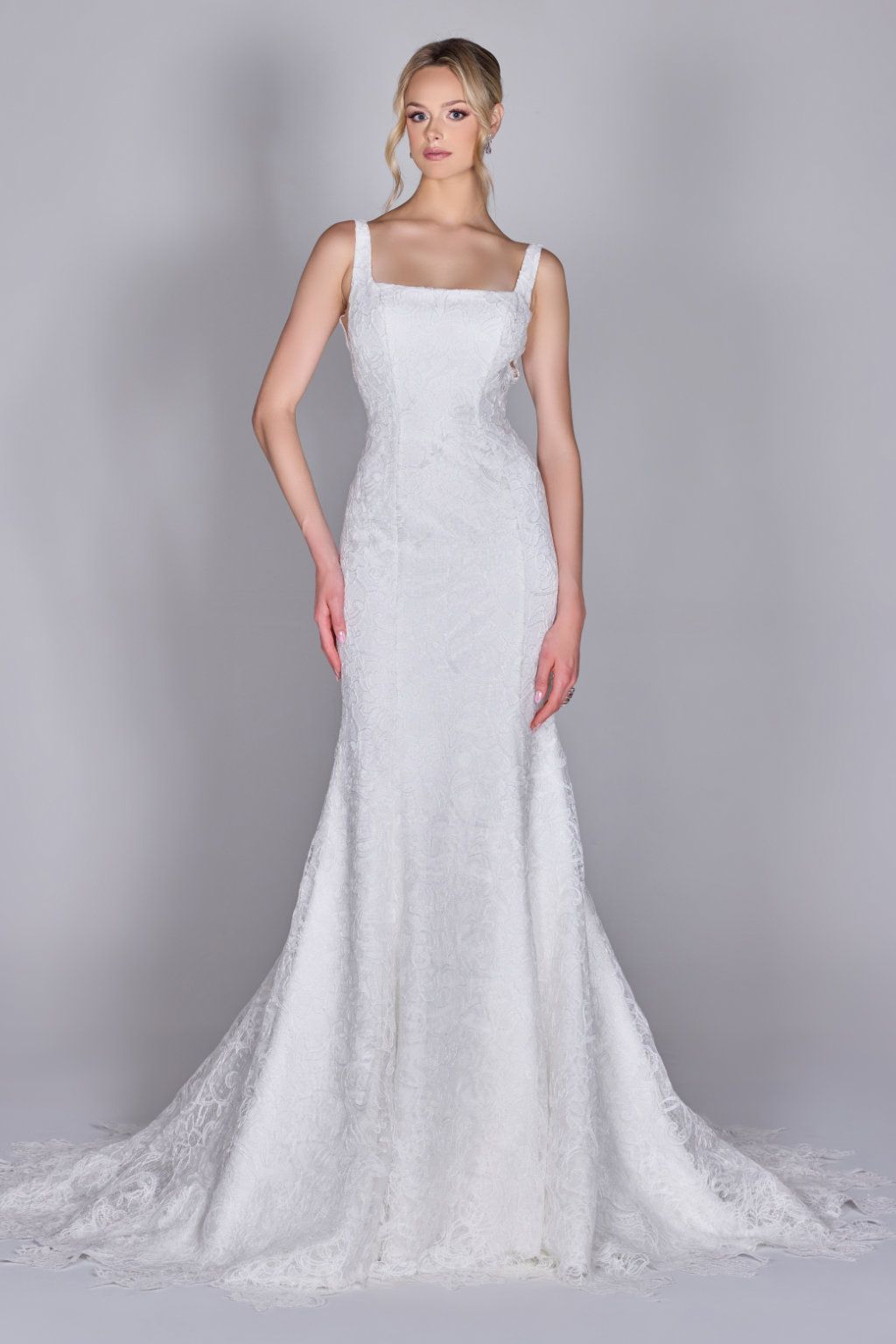 A woman in a white wedding dress is standing in front of a building.