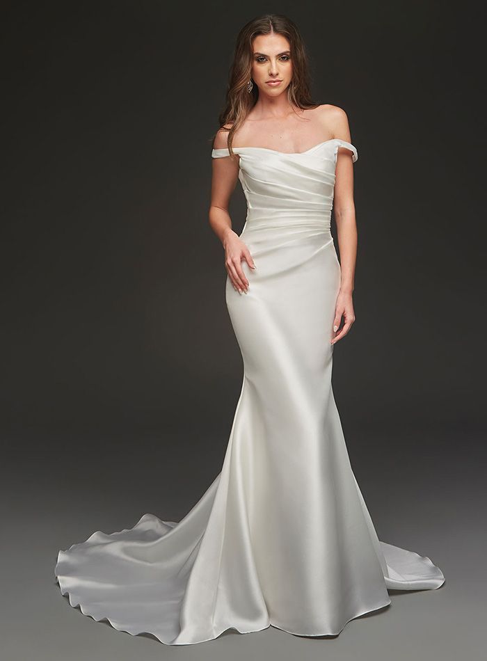 A woman is wearing a white off the shoulder wedding dress.