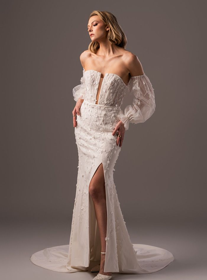 A woman is wearing a white wedding dress with a high slit.