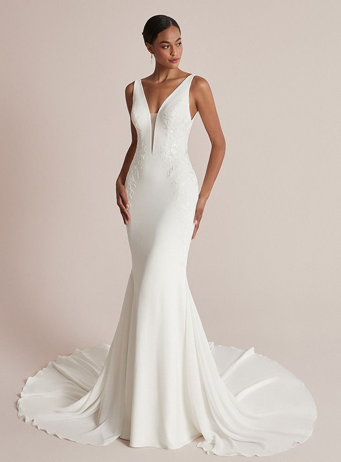 A woman is wearing a white wedding dress with a plunging neckline.