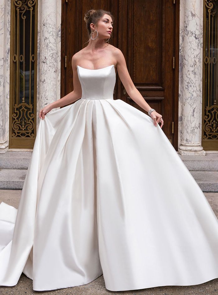 A woman in a white wedding dress is standing in front of a building.