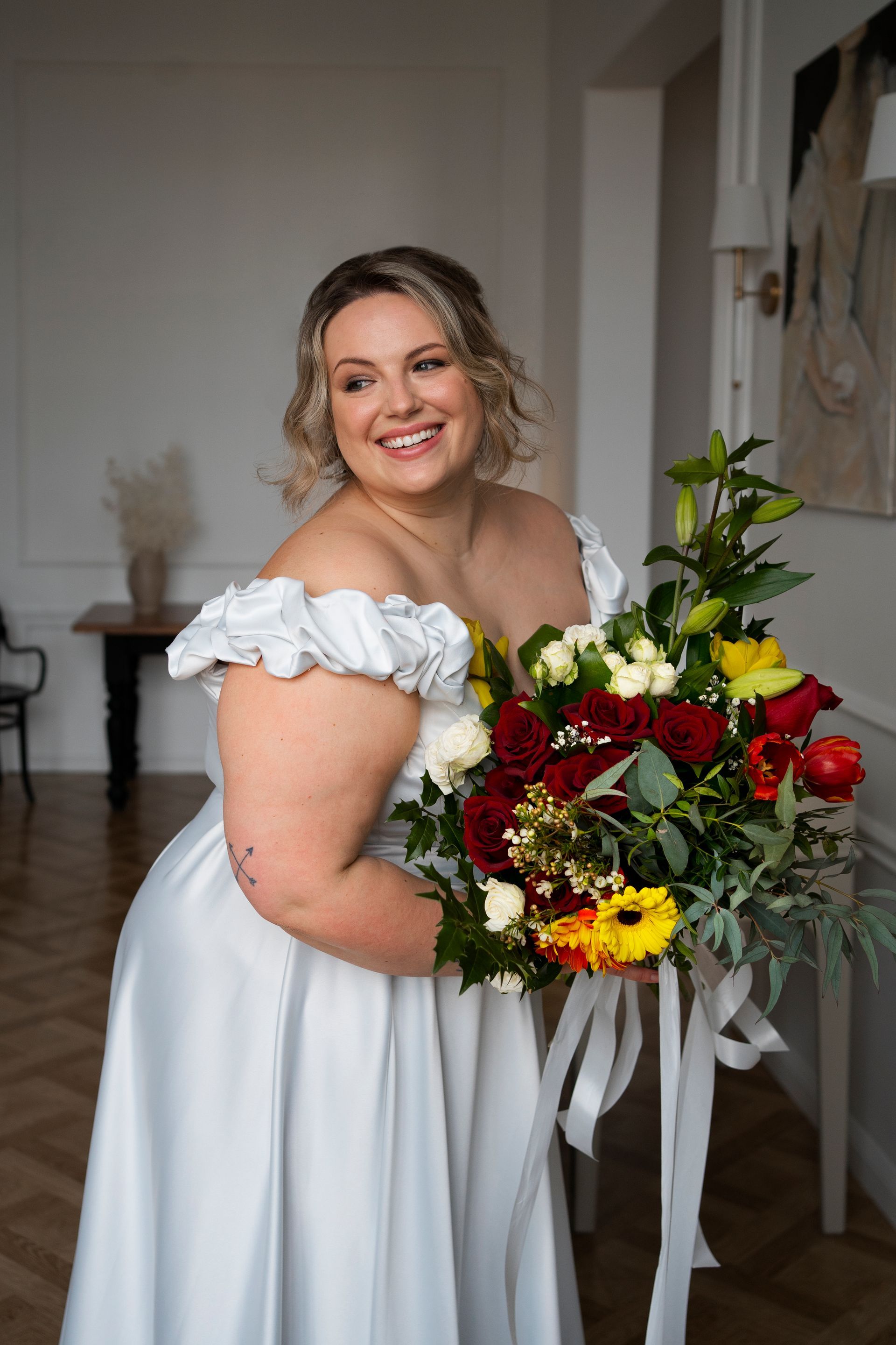 A plus size bride in a white dress is holding a bouquet of flowers.
