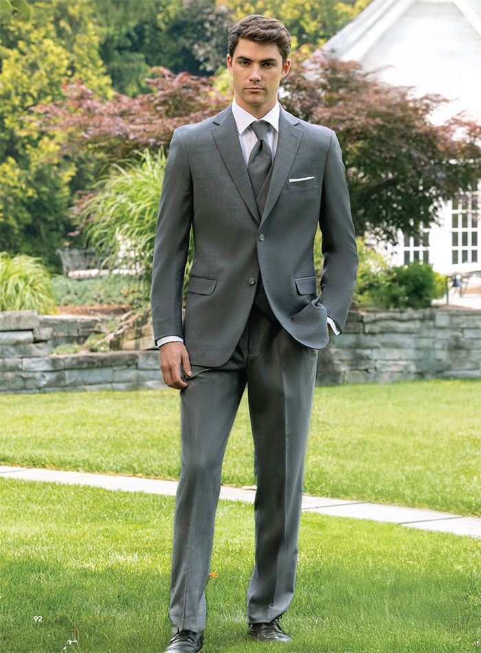 A man in a suit and tie is standing in a grassy field.